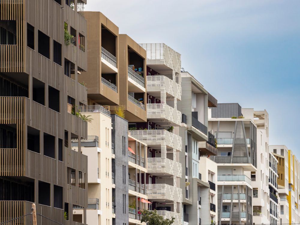 Facades of modern residential buildings with balconies under blue sky in Montpellier, Occitanie
